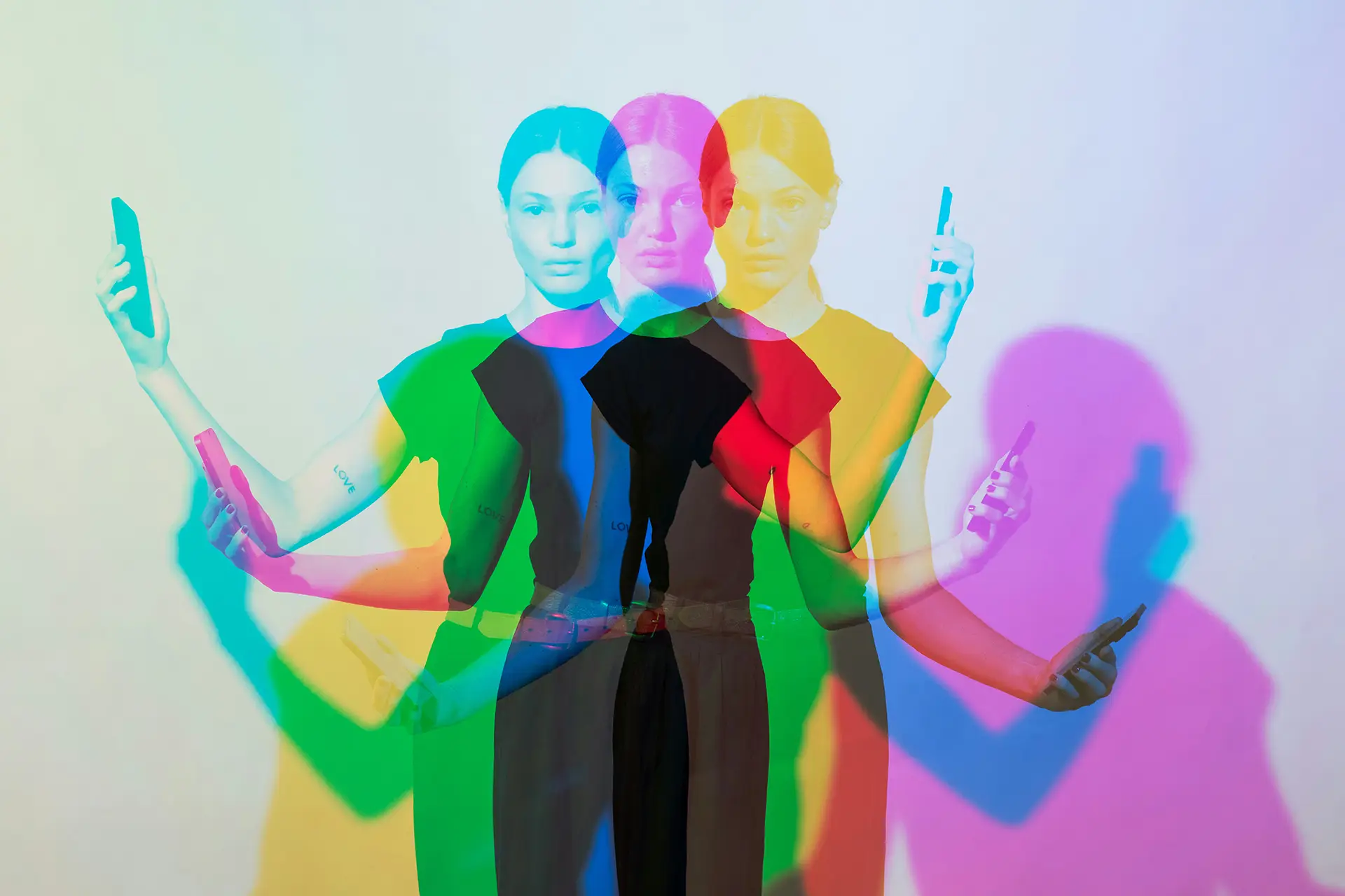 Woman standing with phone in hand shown in overlapping red, green, and blue shadow effects on a white background.